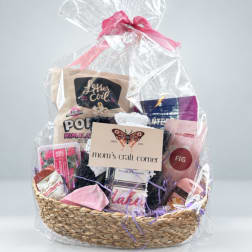 Gift basket with assorted packaged items wrapped in clear cellophane and tied with a pink ribbon