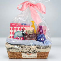 Gift basket with cosmetics and cards in a woven basket tied with a pink bow