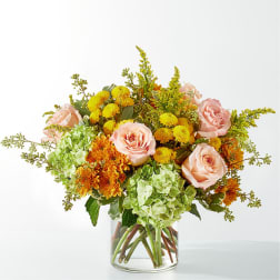 Bouquet of pink roses, green hydrangeas, and yellow-orange mums in a clear glass vase