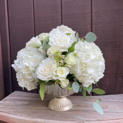 White roses and hydrangeas arranged in a silver pedestal vase