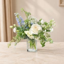 White and blue flowers arranged in a clear glass vase