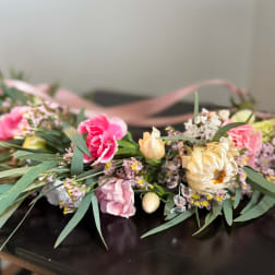 Pink and cream floral arrangement with ribbon on a dark surface