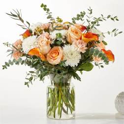 Peach roses and white mums in a clear glass vase