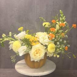 Yellow and white floral arrangement in a pumpkin-shaped vase