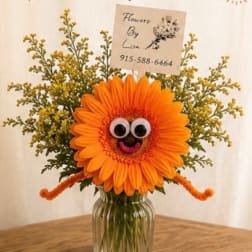 Orange gerbera daisy arrangement with a playful face in a glass vase