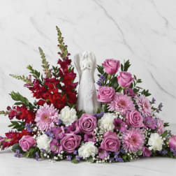 Pink and red floral arrangement with a white angel figurine in the center