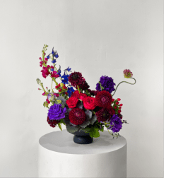 Colorful mixed flower arrangement in a dark vase on a pedestal