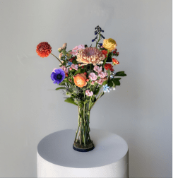 Colorful mixed bouquet in a clear glass vase on a pedestal