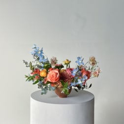 Mixed bouquet of colorful flowers in a small brown vase