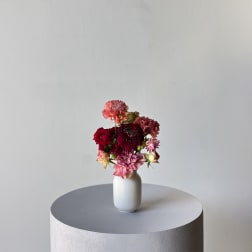 Small mixed flower arrangement in a white vase