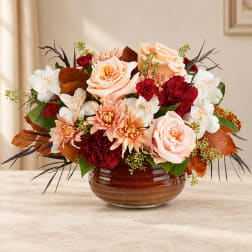 Peach and red floral arrangement in a brown glass bowl vase