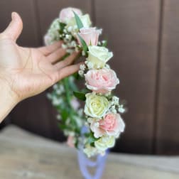 Hand holding a floral crown with pink and white roses