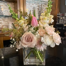 Pink and white floral arrangement in a clear square vase