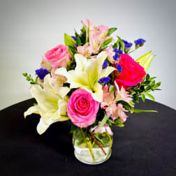 Bouquet of pink roses, white lilies, and pink alstroemeria in a glass vase