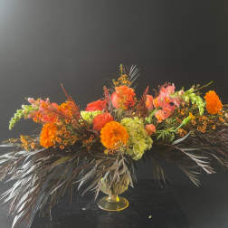 Orange and pink floral arrangement in a gold vase
