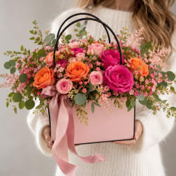 Pink and orange rose arrangement in a pink gift box with ribbon