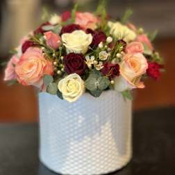 Bouquet of pink, cream, and burgundy roses in a white textured vase