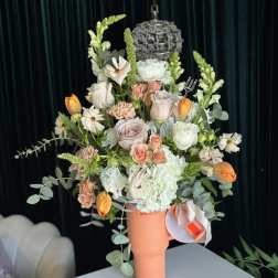 Mixed bouquet of pastel flowers in a coral tumbler vase