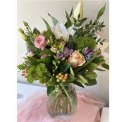 Mixed bouquet of pink, white, and purple flowers in a glass vase