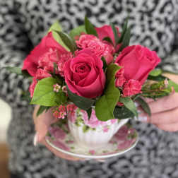 Pink rose and carnation arrangement in a floral teacup and saucer