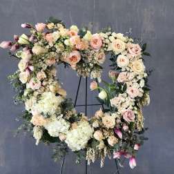Large floral wreath of pastel roses and hydrangeas on a stand