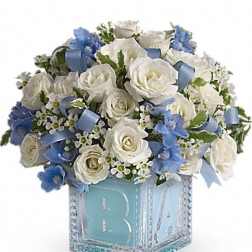 White roses and blue flowers in a decorative cube vase