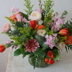 Mixed bouquet of pink, white, and orange flowers in a glass vase