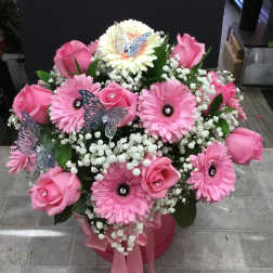 Pink roses and gerbera daisies in a pink box with butterfly picks