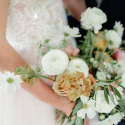 Bride holding a white and peach bouquet with daisy-like blooms