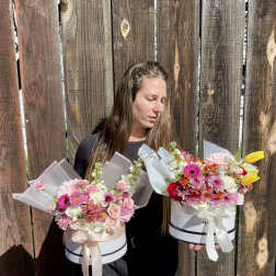 Woman holding two pastel flower boxes with mixed blooms