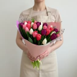 Bouquet of pink, purple, and white tulips wrapped in pale pink paper