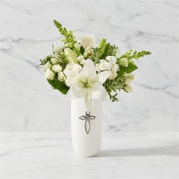 White lily and rose arrangement in a white vase with a cross charm