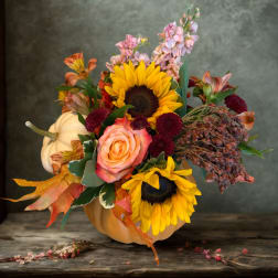 Autumn floral arrangement in a white pumpkin vase with sunflowers and roses