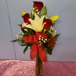 Bouquet of red roses and white lilies in a glass vase with a red ribbon