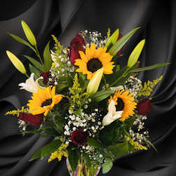 Bouquet of sunflowers, red roses, and white lilies in a glass vase