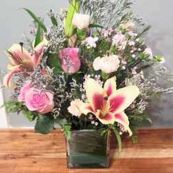 Pink and cream floral arrangement in a square glass vase