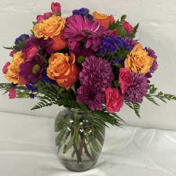 Mixed bouquet of purple, pink, and orange flowers in a glass vase