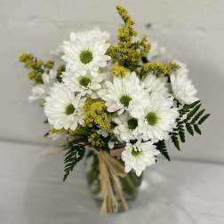 White daisy bouquet with yellow filler in a glass vase