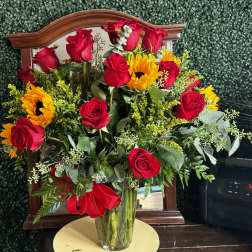 Bouquet of red roses and sunflowers in a clear glass vase