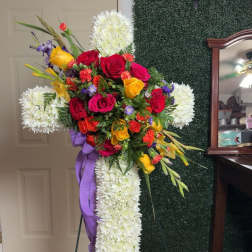 Standing floral cross with red, yellow, and white flowers on an easel