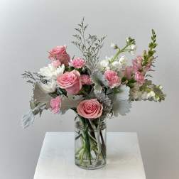 Pink and white flower arrangement with roses and carnations in a clear glass vase