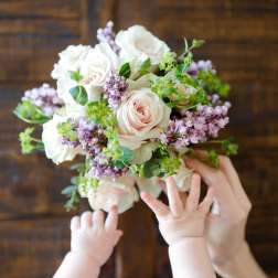 Handheld bouquet of pale pink and white roses with lilac flowers