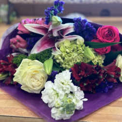 Mixed bouquet with lilies, roses, and hydrangea in purple wrap