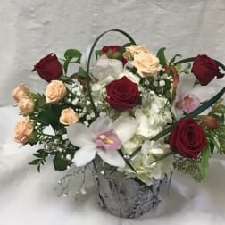 Mixed roses and orchids in a silver container