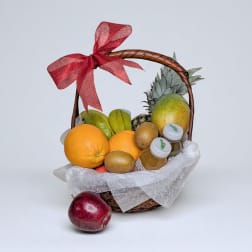 Fruit basket with oranges, mango, kiwi, and bottled juice tied with a red bow
