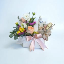 Mixed flower arrangement in a white box with a pink ribbon