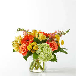 Mixed bouquet in a clear glass vase with orange, yellow, and green blooms