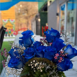 Blue roses arranged in a moss-covered box with small filler flowers