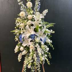 Tall white and blue floral standing spray on an easel