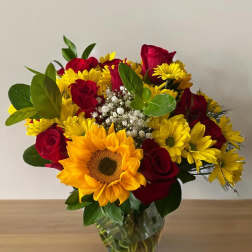Bouquet of red roses and yellow sunflowers in a clear glass vase